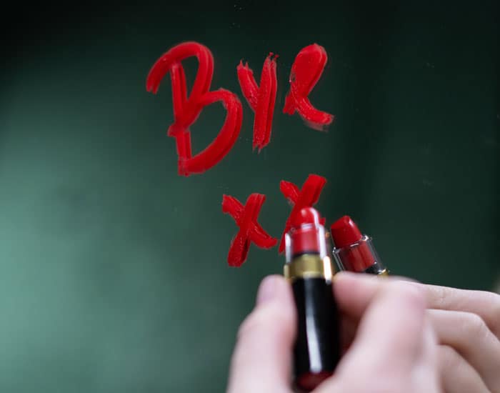 Desperately Seeking Genealogy Software: A Guide to Finding Your Perfect Match 2 Woman's hand writing "Bye XX" on a mirror in red lipstick.