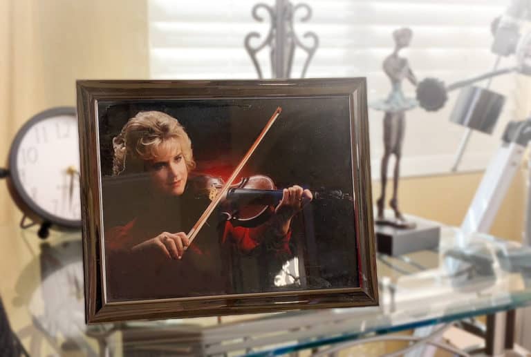 A photograph that is stuck to glass of a girl holding a violin