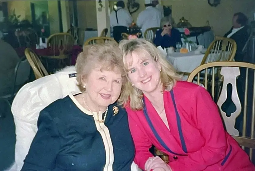 5 (Mostly) Free Apps to Scan Film Negatives With Your Phone 4 Color image scanned from a film negative with the Filmory app: two women, an older red-haired woman in a black and white suit next to a younger blonde woman in a red suit with dark blue trim.