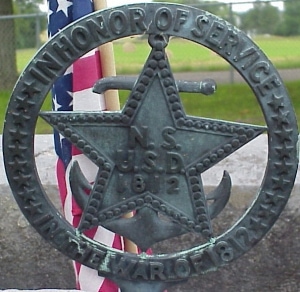 Researching Your War of 1812 Ancestors Online 8 Image of a War of 1812 grave marker placed by the National Society United States Daughters of 1812; round metal circle with a star and anchor in the middle.