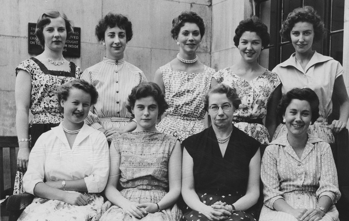 Black and white image dated 1956 of five women standing and four women seated.