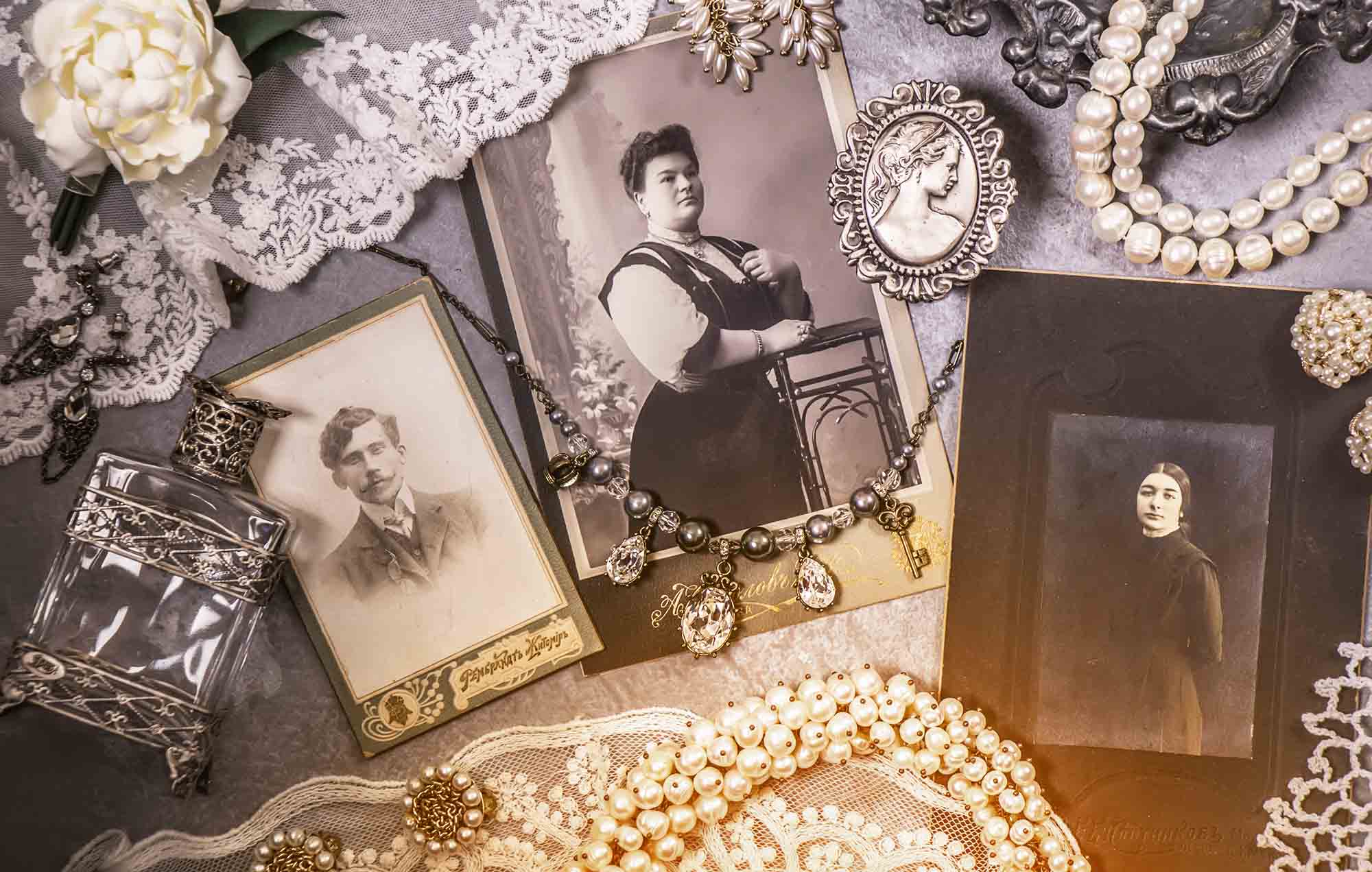 Old sepia photos, lace, and jewelry arranged on a table.