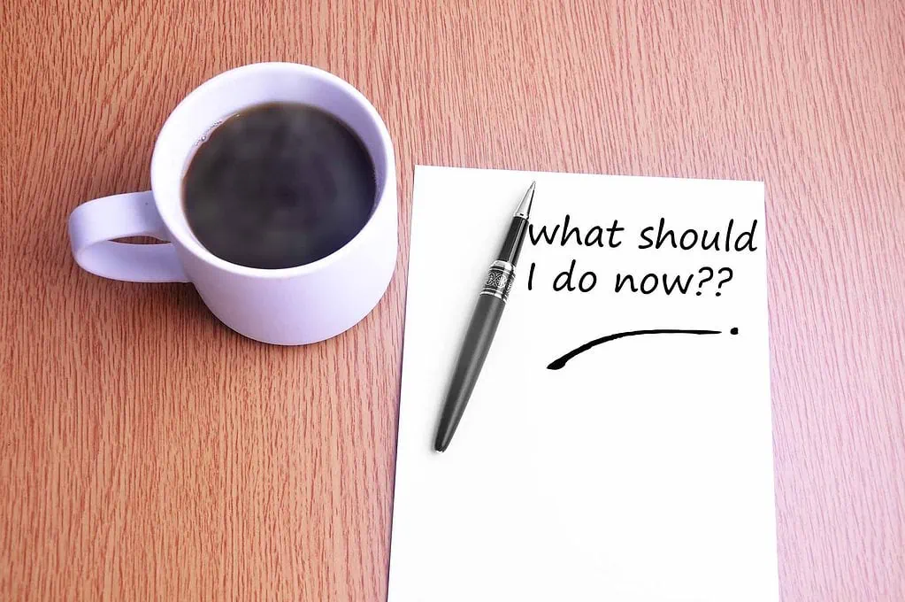 10 Best Strategies for Researching "Brick Wall" Ancestors 2 Coffee in a white mug, a black and silver pen, and note paper with "what should I do now?" in black ink.